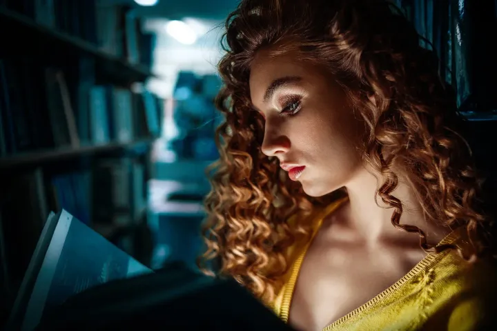 woman reading book in dark room